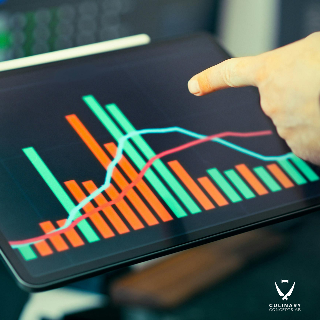 Close-up of a finger pointing at a tablet screen displaying a red and green bar chart with a blue line graph, plus a logo in the corner.