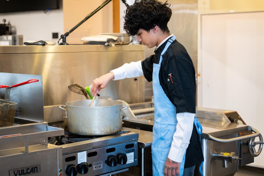 Culinary student stirring a large pot
