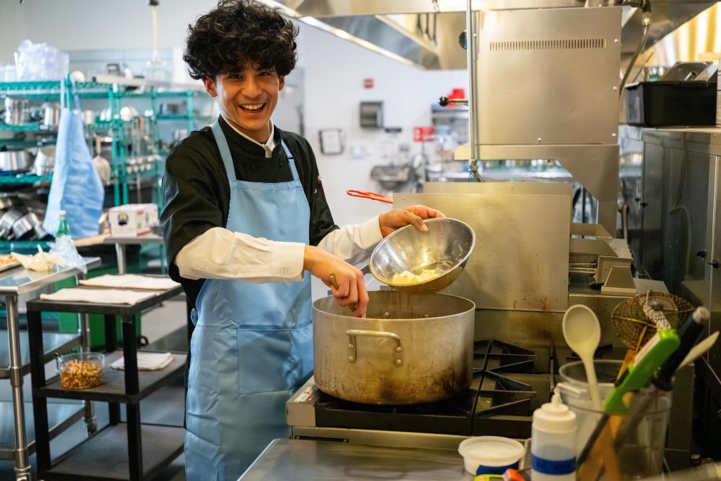 Student in the GO Cook program adding butter to a pot