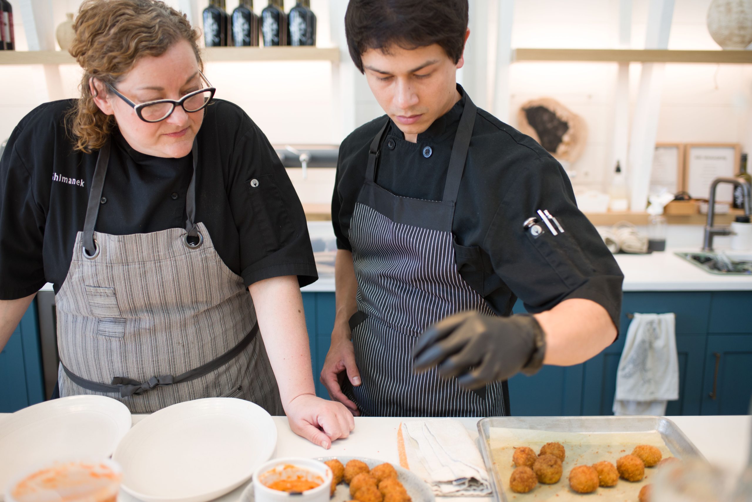 A CCAB chef coaching a young cook as he plates